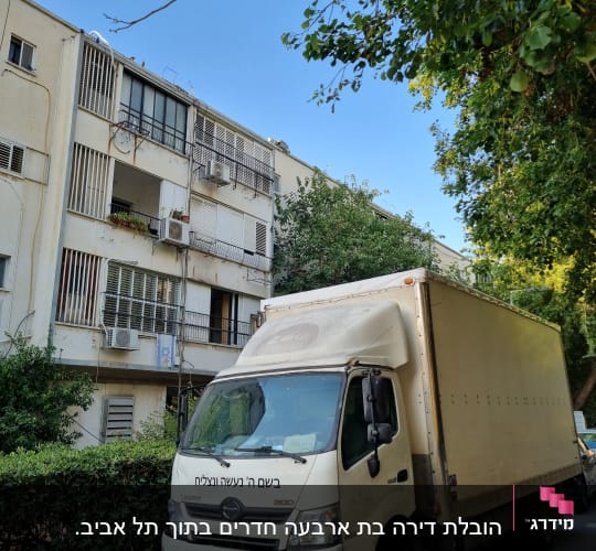 משאית חונה ליד בניין מגורים עם עצים ברקע